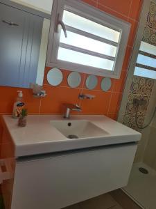 baño con lavabo blanco y ventana en L appart du trou d eau, en La Saline-Les-Bains