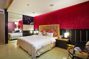 薇風情汽車旅館 - 台南館 في Liujia: غرفة نوم بسرير كبير وجدار احمر