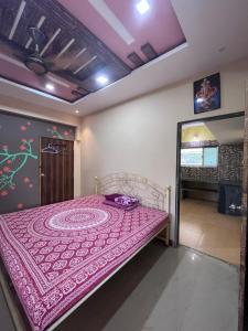 1 dormitorio con 1 cama con colcha púrpura en Patil Homestay, en Alībāg