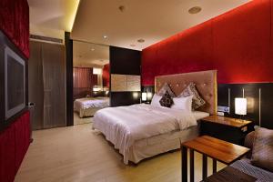 薇風情汽車旅館 - 台南館 في Liujia: غرفة نوم بسريرين وجدار احمر