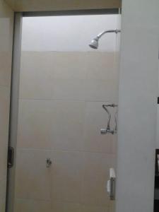 a shower in a bathroom with a glass door at Rumah Tourist in Banyuwangi