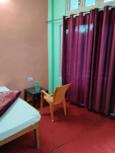 Zimmer mit einem Bett und einem Stuhl sowie lila Vorhängen in der Unterkunft Shri Narayan Tourist lodge & Chandica hotel in Trijugi Nārāyan