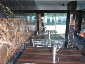 ein Restaurant mit Holztischen und einer Steinmauer in der Unterkunft Shri Narayan Tourist lodge & Chandica hotel in Trijugi Nārāyan