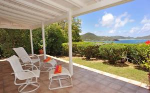 a porch with white chairs and a view of the ocean at Saint Barth Villa 7 in Pointe Milou
