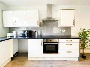 a kitchen with white cabinets and a black counter top at Chic City Loft Room in Liverpool