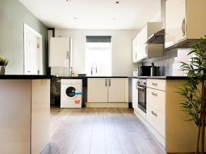 a kitchen with white cabinets and a washer and dryer at Chic City Loft Room in Liverpool