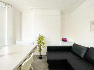 a living room with a black couch and a potted plant at Sleek Minimalist Room in Liverpool