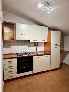 a kitchen with white cabinets and a stove top oven at Sicilia Bedda Apartment in Messina