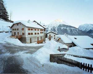 ein schneebedecktes Dorf mit Bergen im Hintergrund in der Unterkunft Tablà Heustall Piz Tschütta in Vna