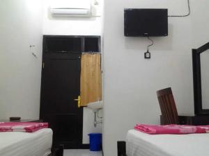 a room with two beds and a door and a television at Rumah Tourist in Banyuwangi