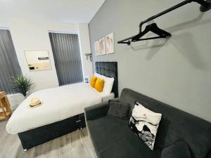 a bedroom with a bed and a couch in front of it at Urban and stylish Central Studio Apartment in Liverpool with high speed free wifi in Liverpool