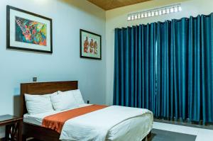 a bedroom with a bed and blue curtains at Nyumbani Cottages Kicukiro in Kigali