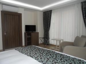 ŞarköyにあるZen Inn Boutiqueのベッド、ソファ、テレビが備わるホテルルームです。