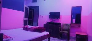 a pink room with a bed and a tv at Hotel Sonali in Lataguri