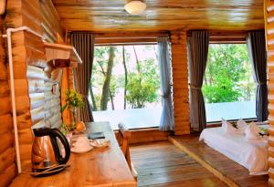 a room with a bed and a table and a window at Phu Ninh Lake Resort & Spa in Tam Ky