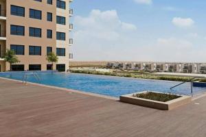 una piscina frente a un edificio en StoneTree - Furnished 1BR in Peaceful Community en Dubái