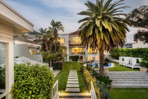 an exterior view of a house with a palm tree at The Clarendon - Fresnaye in Cape Town