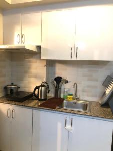 a kitchen with white cabinets and a sink at Darling Vacation Rental Davao City in Davao City