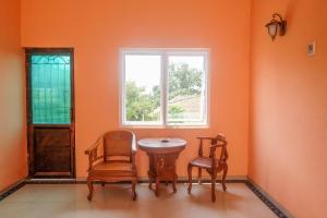 um quarto com uma mesa e duas cadeiras e uma janela em RedDoorz Syariah @ Klodran Solo em Kadipiro