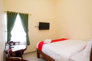 a bedroom with a bed and a desk and a window at RedDoorz Syariah @ Klodran Solo in Kadipiro