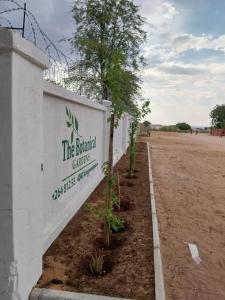 a white wall with a sign that says the biblical garden at River Gates Guesthouse in Rundu