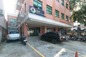 un bâtiment avec deux voitures garées dans un parking dans l'établissement M28 Hotel and Apartments Quezon City, à Manille