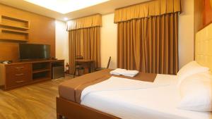 Cette chambre comprend un lit et une télévision à écran plat. dans l'établissement M28 Hotel and Apartments Quezon City, à Manille