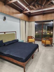 1 dormitorio con 1 cama grande y 2 sillas en Shantramniy 4bhk the Villa, en Bhuj
