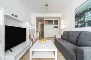 uma sala de estar com um sofá cinzento e uma televisão em Home2Book Charming Apartments La Naval La Isleta em Las Palmas de Gran Canaria