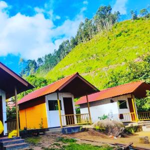 a house with a green hill in the background at Vattavada Jungle Resort in Munnar +18 photos