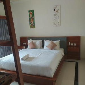a bedroom with a bed with white sheets and pillows at d'Leisure Guest House in Uluwatu +10 photos