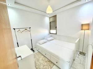 - une chambre blanche avec un lit et une fenêtre dans l'établissement A3 Appartement entièrement neuf au cœur de Témara, à Temara