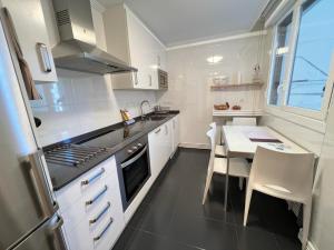 a kitchen with white cabinets and a table and a sink at ELCANO Bermeo 2 in Bermeo