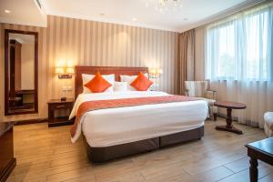 Pokój hotelowy z dużym łóżkiem z pomarańczowymi poduszkami w obiekcie Sarova Woodlands Hotel and Spa w mieście Nakuru
