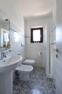 een witte badkamer met een wastafel en een toilet bij Residence il Melograno in San Teodoro