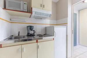 eine Küche mit einer Spüle, einer Mikrowelle und einem Kühlschrank in der Unterkunft Appart'City Classic Limoges in Limoges