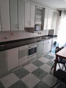 a kitchen with white cabinets and a checkered floor at Apartamento la catedral in Santo Domingo de la Calzada