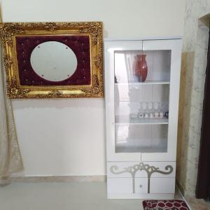 un miroir assis sur un mur à côté d'une étagère dans l'établissement العين الهيلي مصباح بيت 3, à Al-Aïn