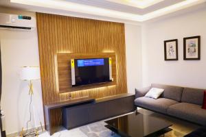 a living room with a couch and a television on a wall at Omah Apartments in Abuja