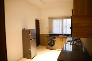 a kitchen with a refrigerator and a washing machine at Omah Apartments in Abuja