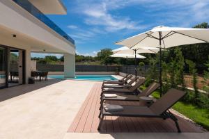 een rij ligstoelen en een parasol naast een zwembad bij Villa Perla in Nova Vas