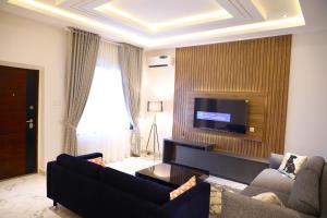 a living room with two couches and a flat screen tv at Omah Apartments in Abuja