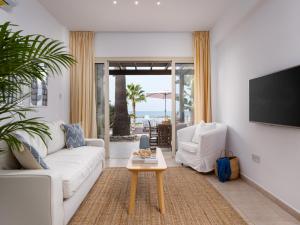 a living room with a white couch and a tv at Kyma I - Beachfront Residence At Latsi in Polis Chrysochous