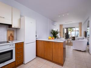 a kitchen with wooden cabinets and a white refrigerator at Kyma I - Beachfront Residence At Latsi in Polis Chrysochous +21 photos