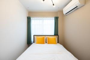 東京にあるbelle ville Kagurazakaのオレンジ枕2つ付きのベッド1台