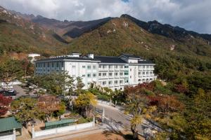 a large white building in front of a mountain at Hotel Gaya in Songju