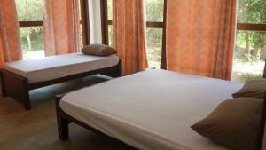 dwa łóżka w pokoju z oknem w obiekcie Forest Edge Bungalow - Wilpattu w mieście Radagama