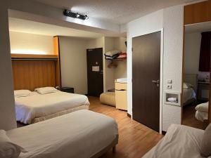 エヴルーにあるBrit Hotel La Bonne Etapeのベッド2台とドアが備わるホテルルームです。