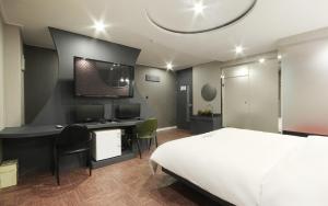 - une chambre avec un lit et un bureau avec un ordinateur dans l'établissement Rosso Hotel, à Busan