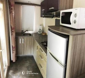 a small kitchen with a microwave and a refrigerator at Villaggio Camping Golfo di Arzachena in Cannigione